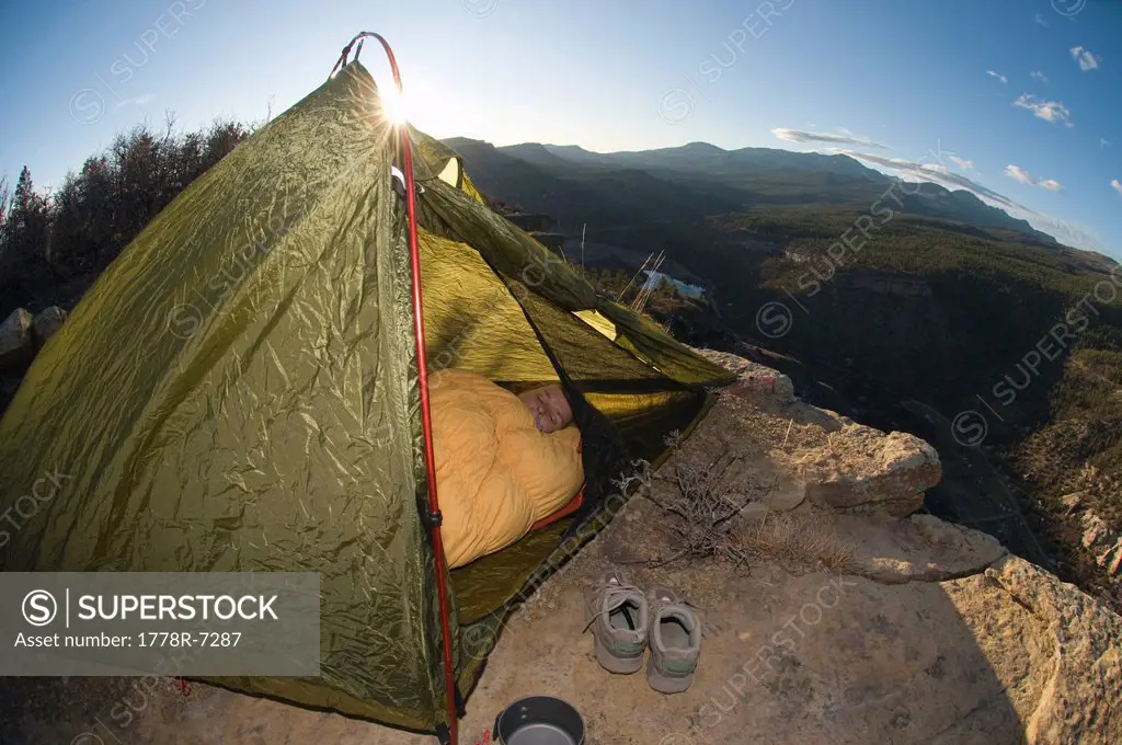 A woman in tent in sleeping bag at sunset on Animas Mountain, Durango, Colorado.