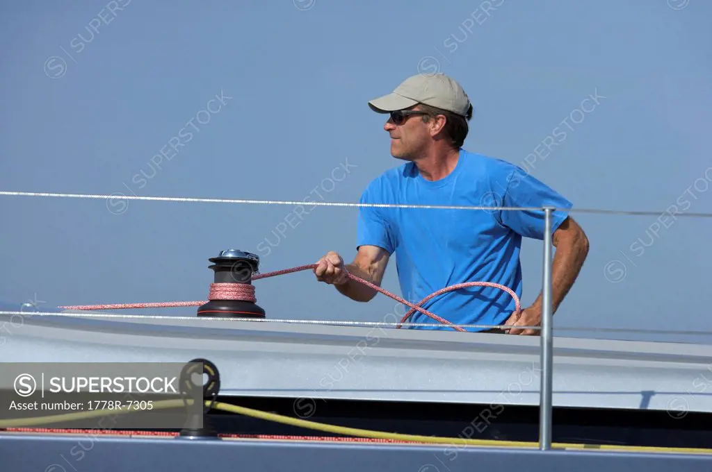 A crew member trims sheet onboard sailing yacht.