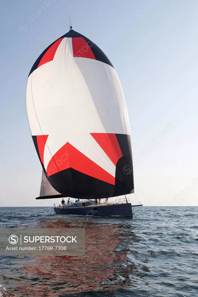 A crew races a modern ocean_going sailing yacht under spinnaker.