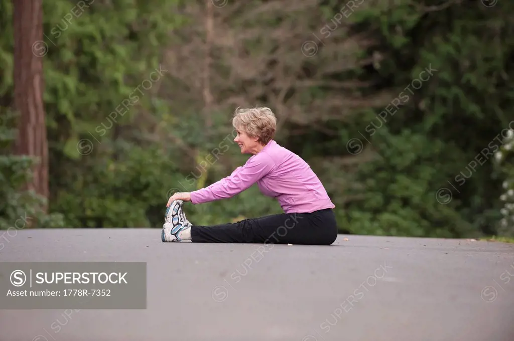 A middle aged woman exercising in a city park.