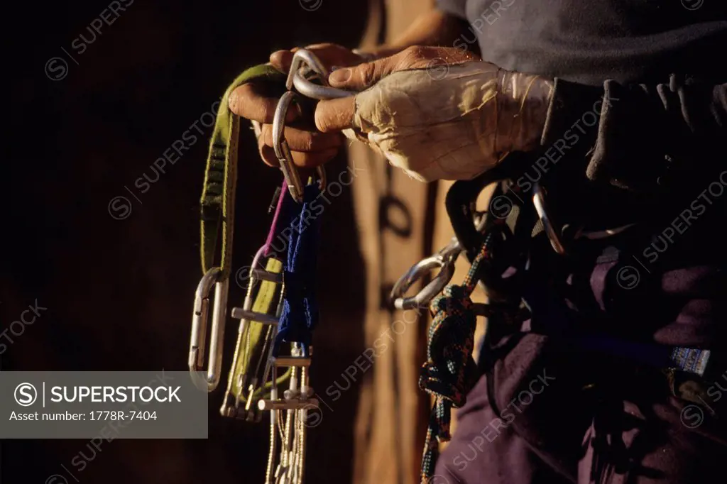 Climber sorting equipment, Indian Creek, Utah. The taped hands protect against the abrasions of the rock.