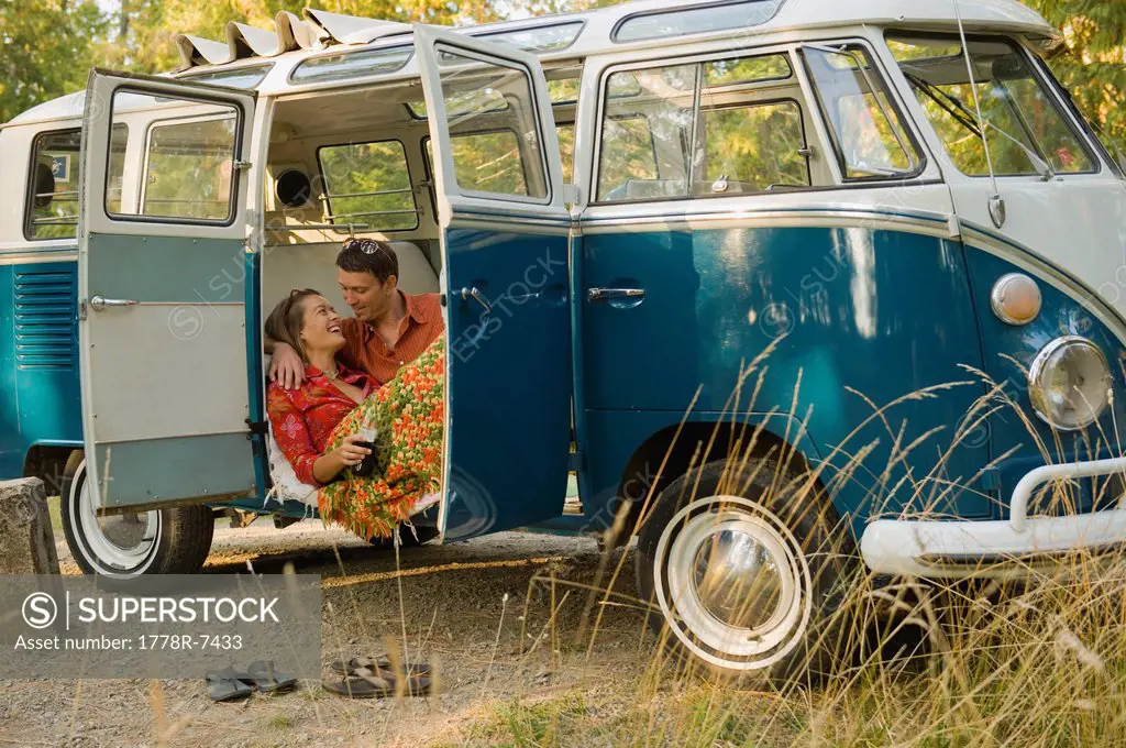 A young couple relax inside a classic van.