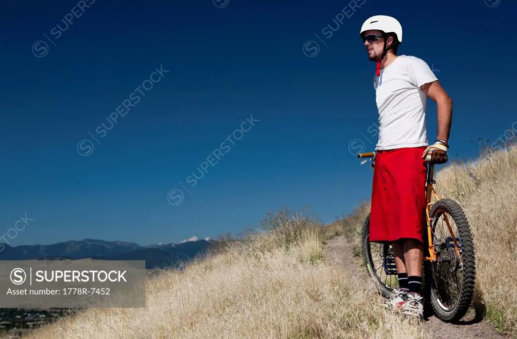 A male mountain biker stops to enjoy the view while riding the trails on Mt. Sentinel, Missoula, Montana.