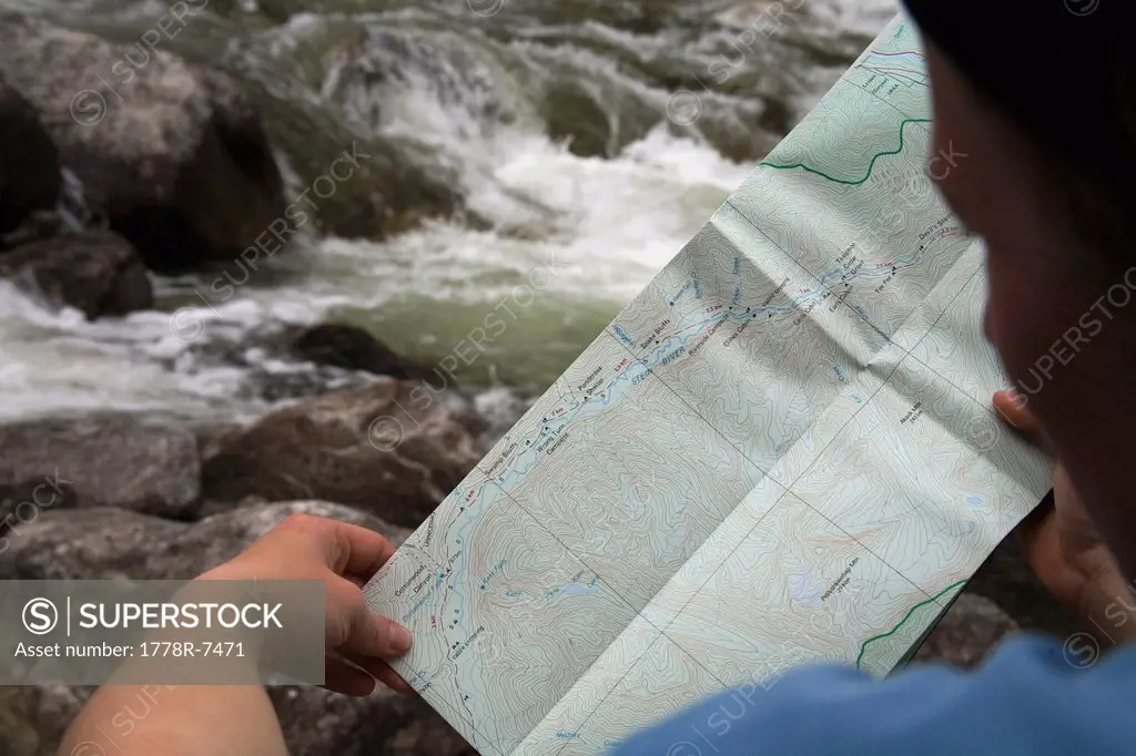 A female hiker in her early thirties navigates with a topographic map while hiking in the Stein Valley. The Stein River is in the background.