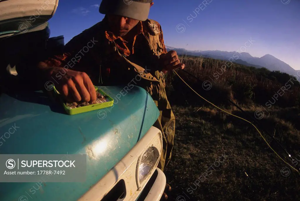 A man picks a fly from his fly box while fishing in Bishop, California.