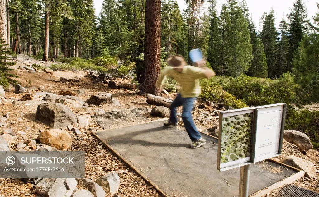 A young man tees off with a distance driver during a game of disc golf in Lake Tahoe, California.