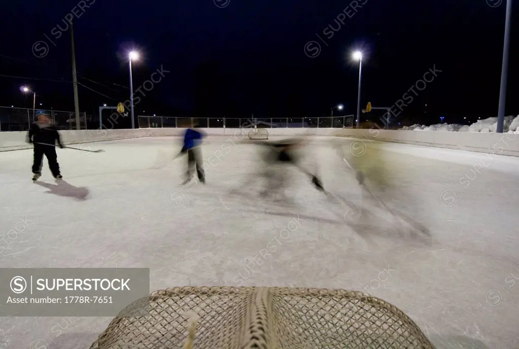 A family plays a game of pick_up hockey at the local elementary school´s ice skating rink in Anchorage, Alaska.