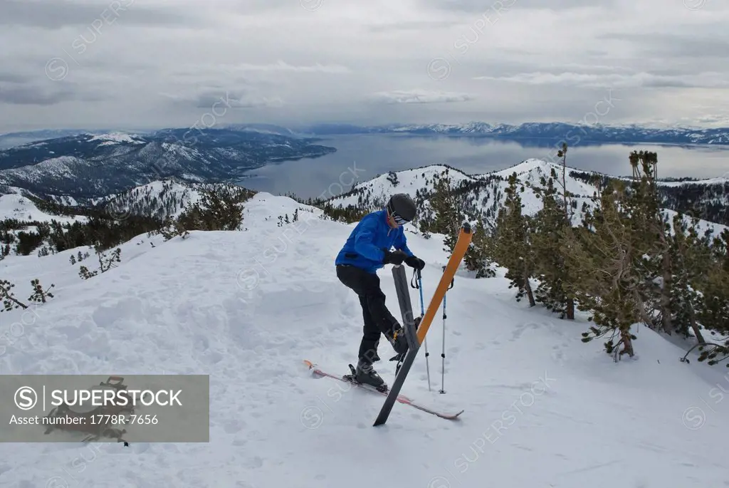 A young man takes his skins off his skis after skinning up a mountain high above Lake Tahoe, Nevada.