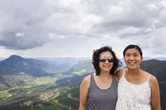 A Japanese American Mother and Daughter stand at Rainbow Curve Overview, with Rocky Mountain National Park stretching out behind them.