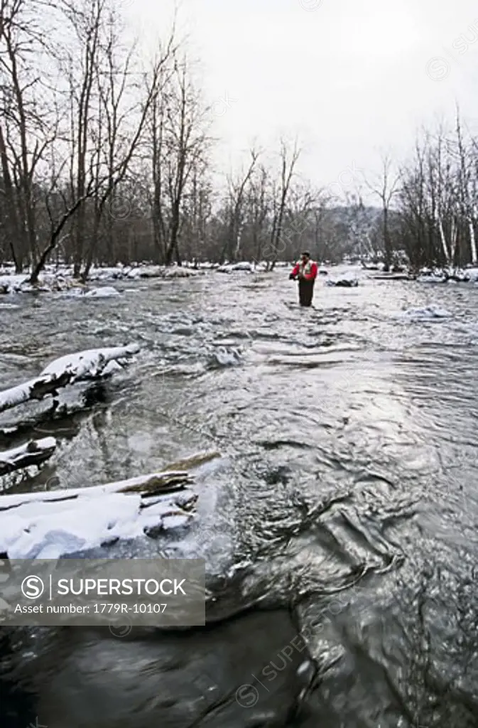 Fly fisherman wading in river