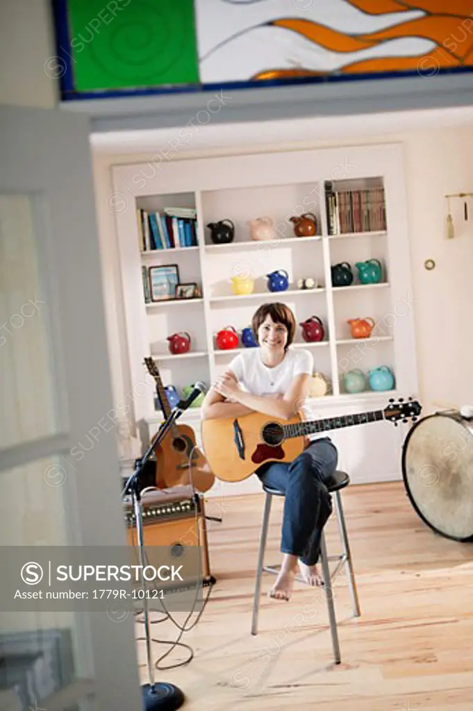 Young woman holding acoustic guitar with amplifier