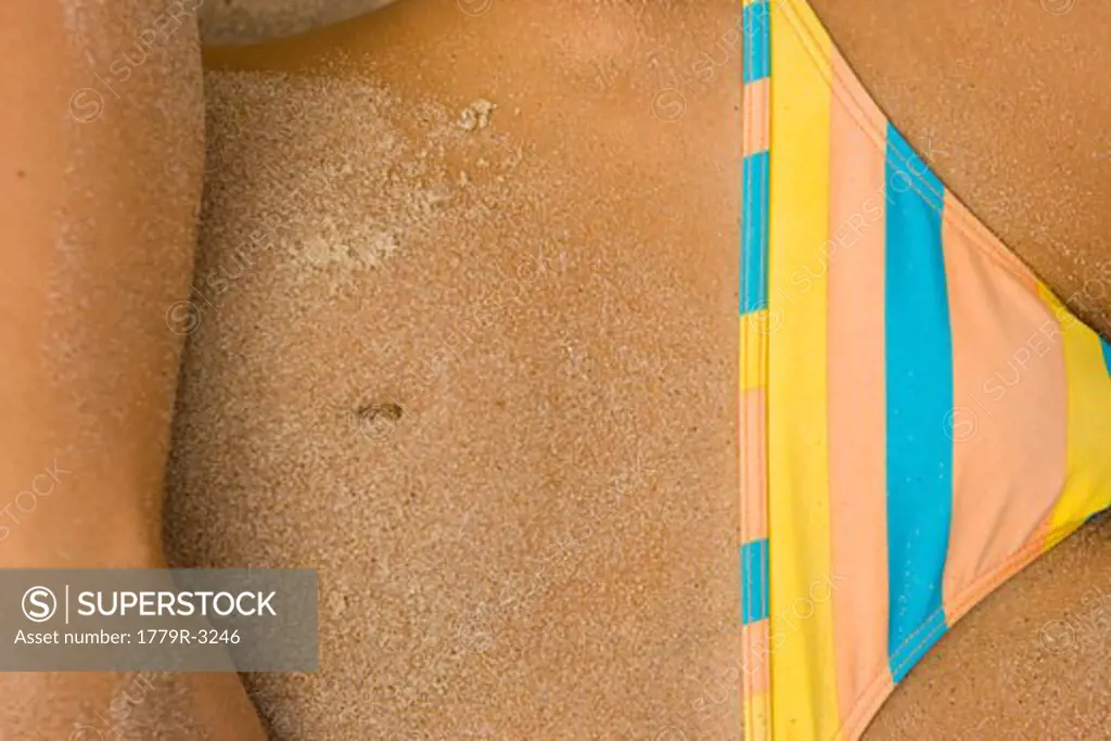 Close-up of sand on woman's midriff