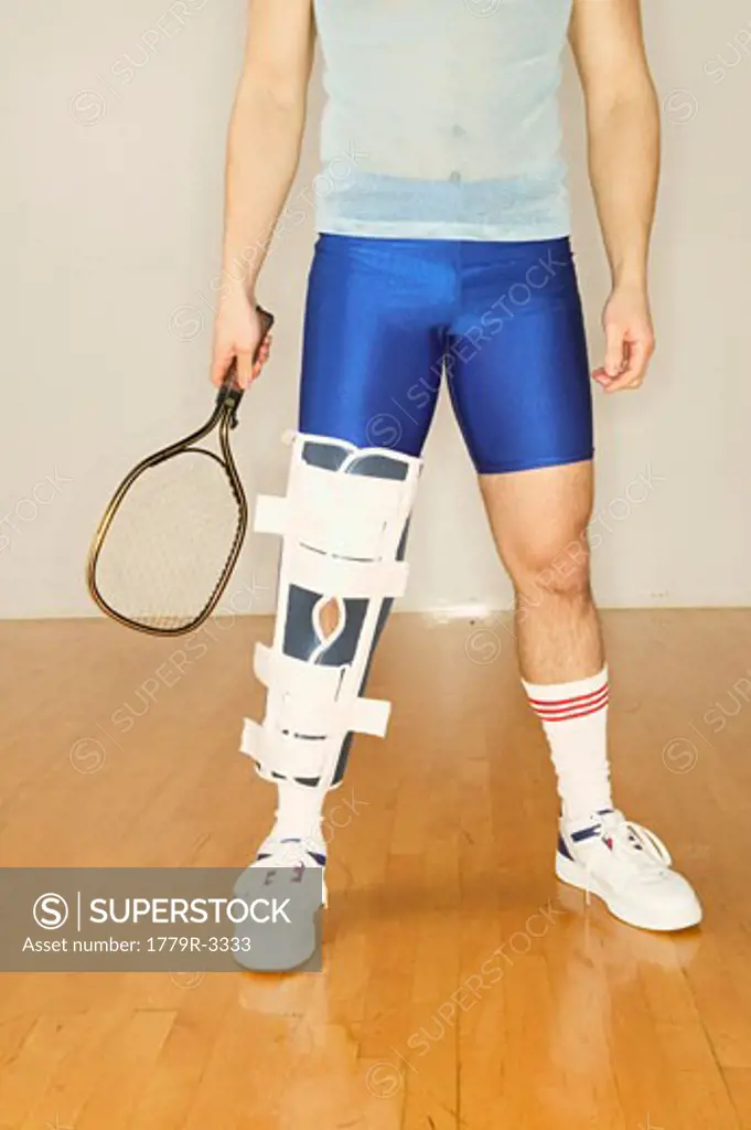 Man in leg brace holding racquetball racket