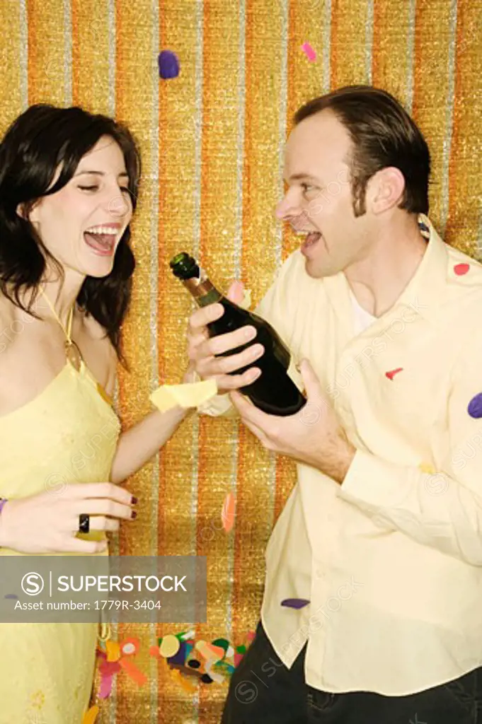 Couple opening bottle of champagne
