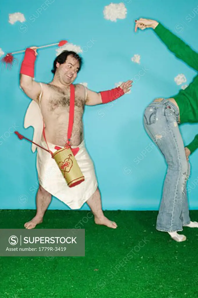Man in Cupid costume throwing arrow at woman's buttocks 