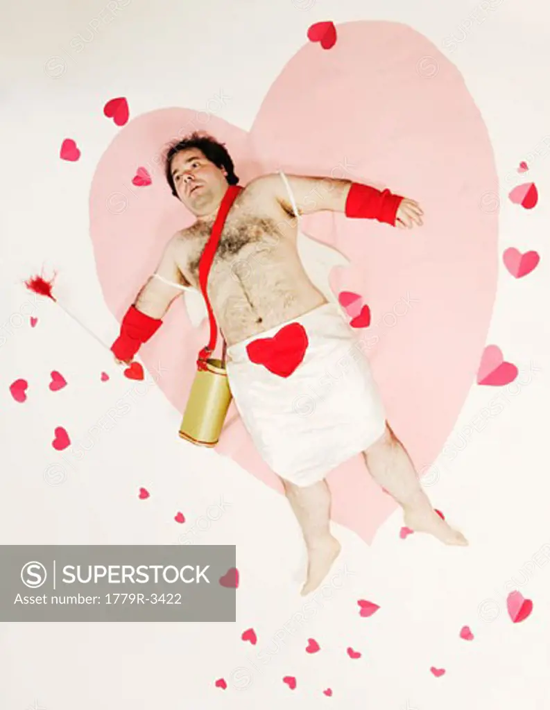 Man in Cupid costume on heart-shaped blanket