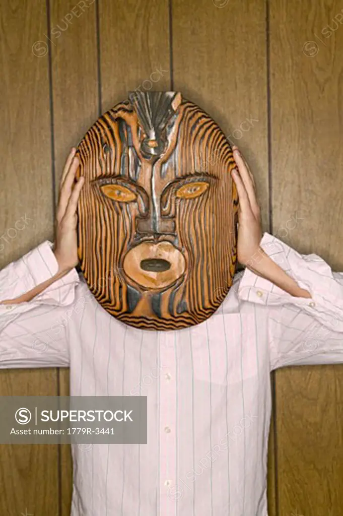 Man holding wooden mask over his face