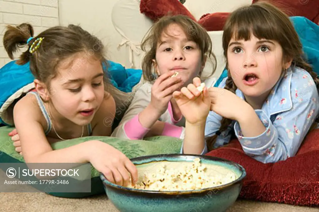 Young girls eating popcorn at a sleepover