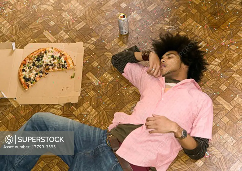African man asleep after pizza and beer feast
