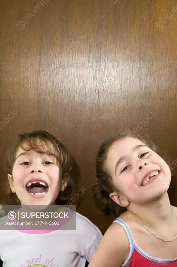 Young girls displaying their missing teeth