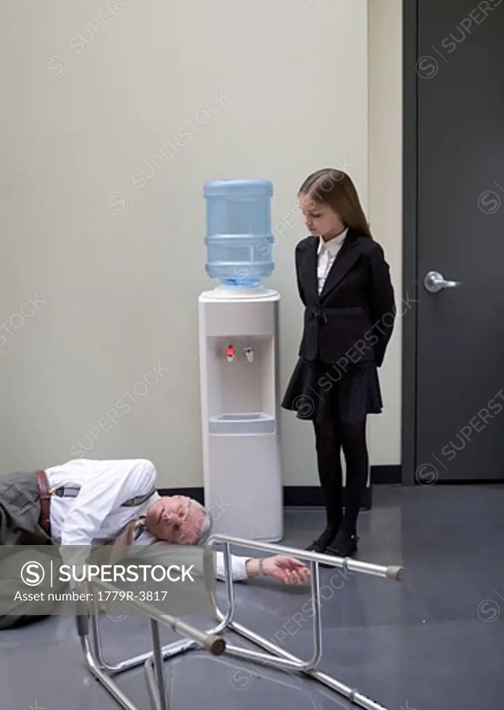 Young girl examining fallen aging businessman by water cooler