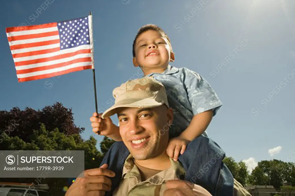 Hispanic military soldier holding son on shoulders