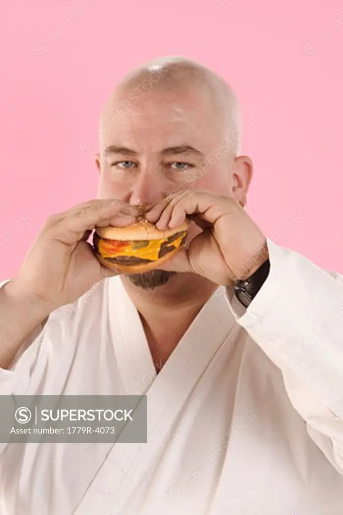 Man in karate outfit eating hamburger