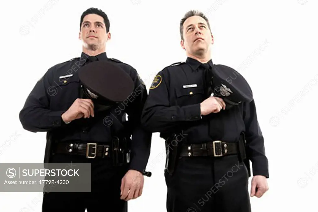 Male police officers holding their hats over their chest