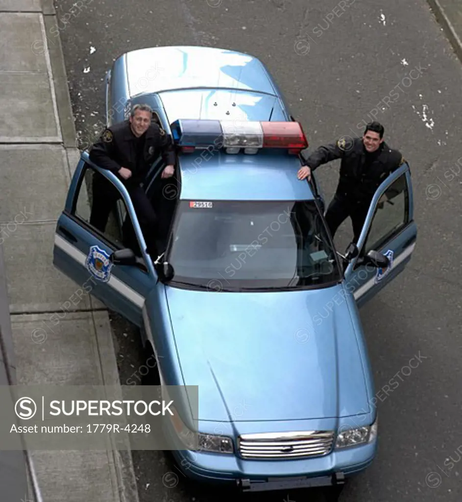 High angle view of male police officers smiling by patrol car