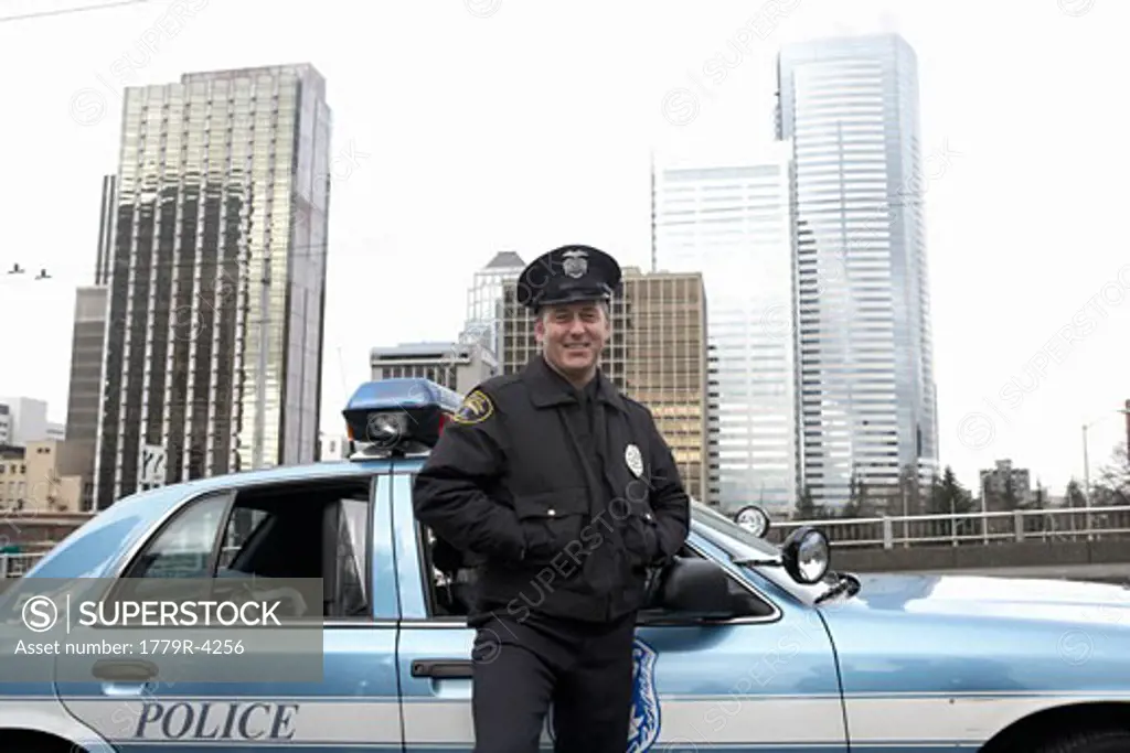 Male police officer smiling by patrol car