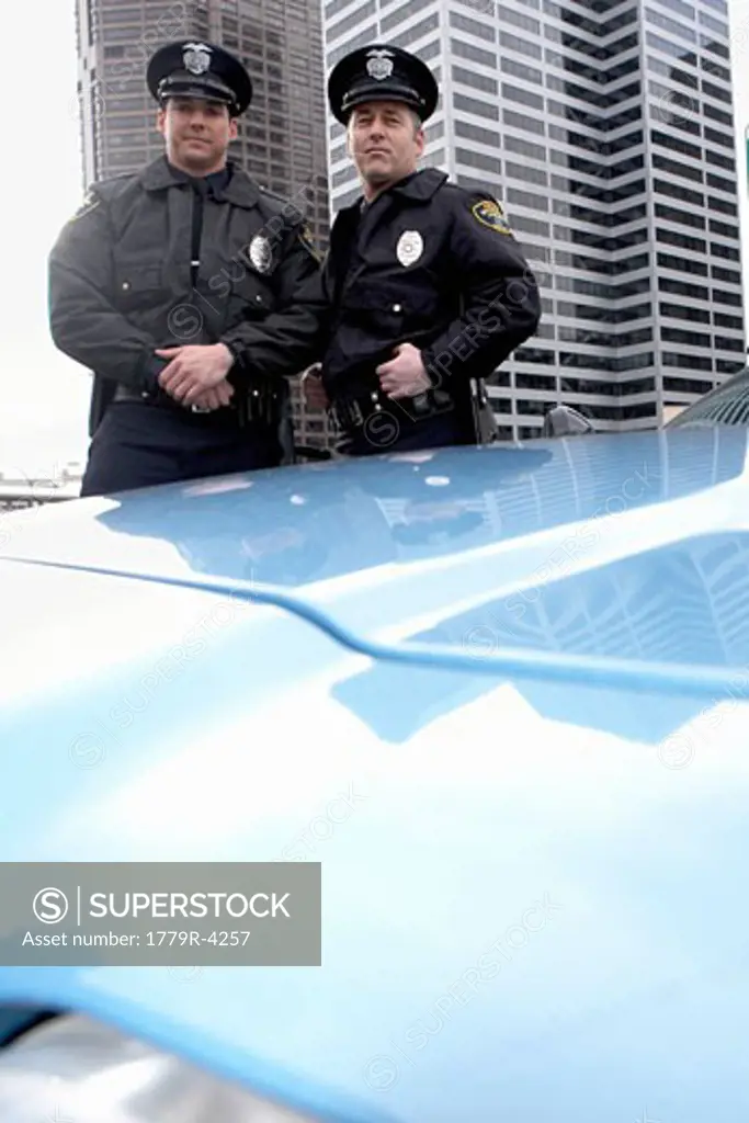 Male police officers standing by patrol car