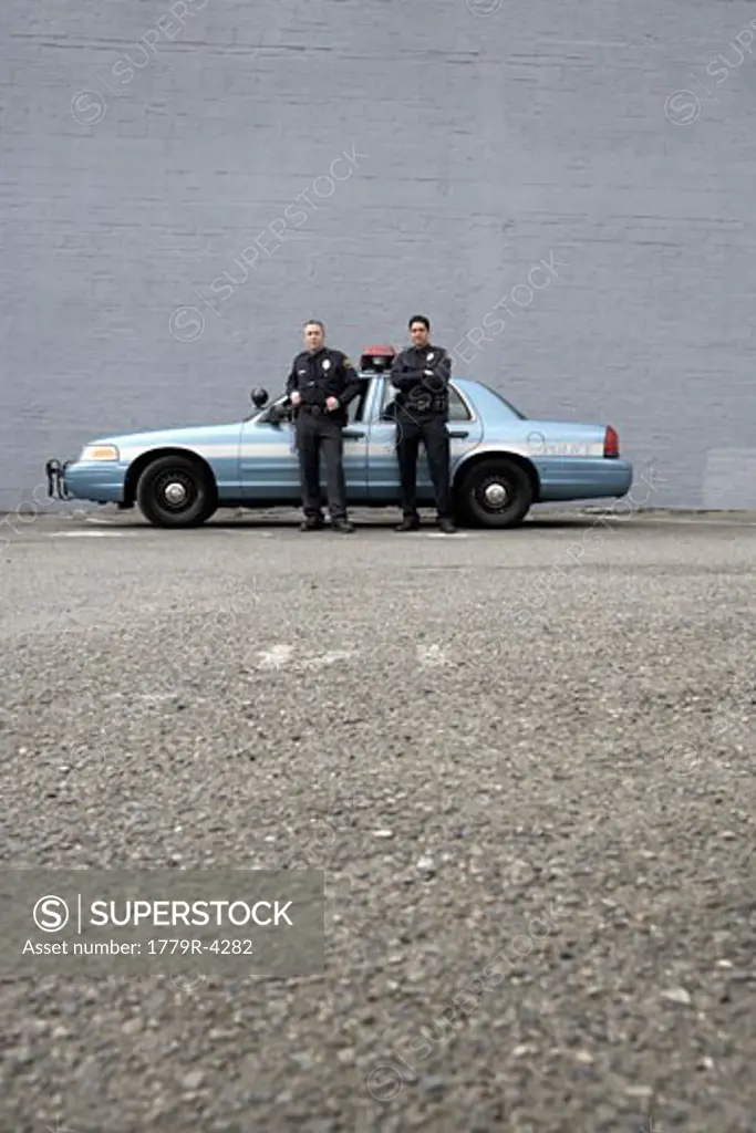 Male police officers standing by patrol car