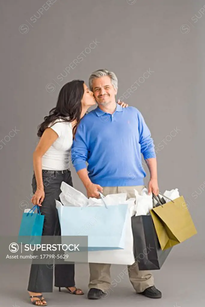 Daughter kissing father holding shopping bags
