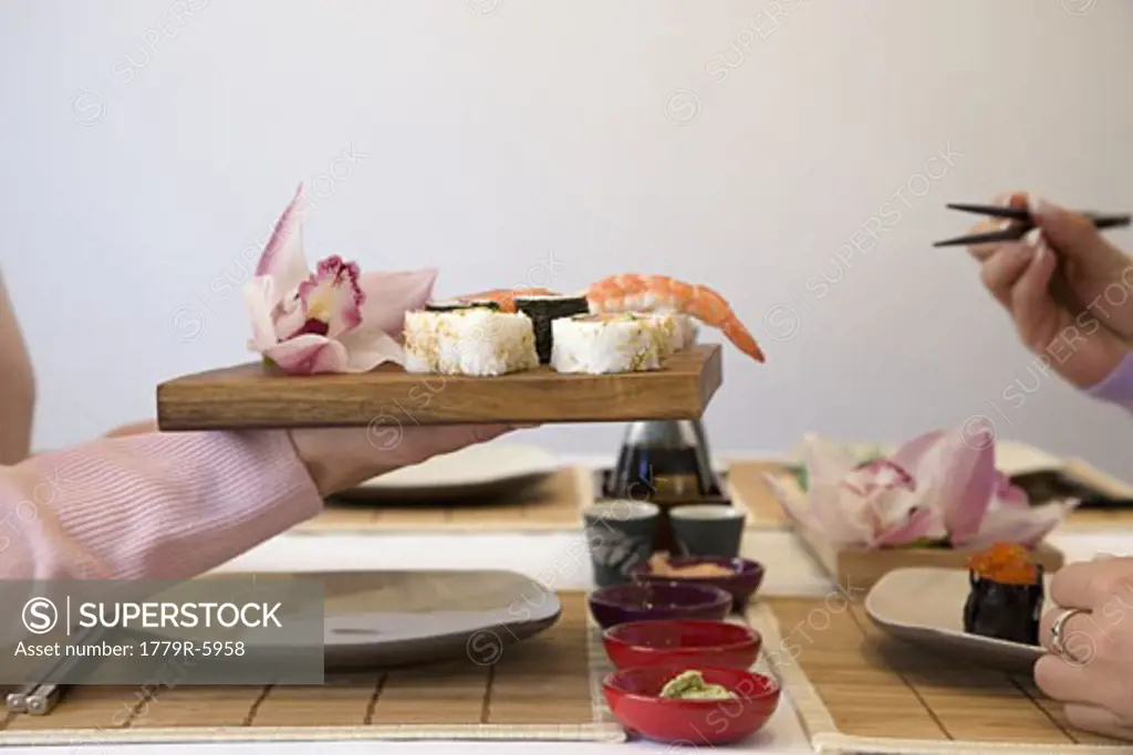 Woman's hand holding tray of sushi