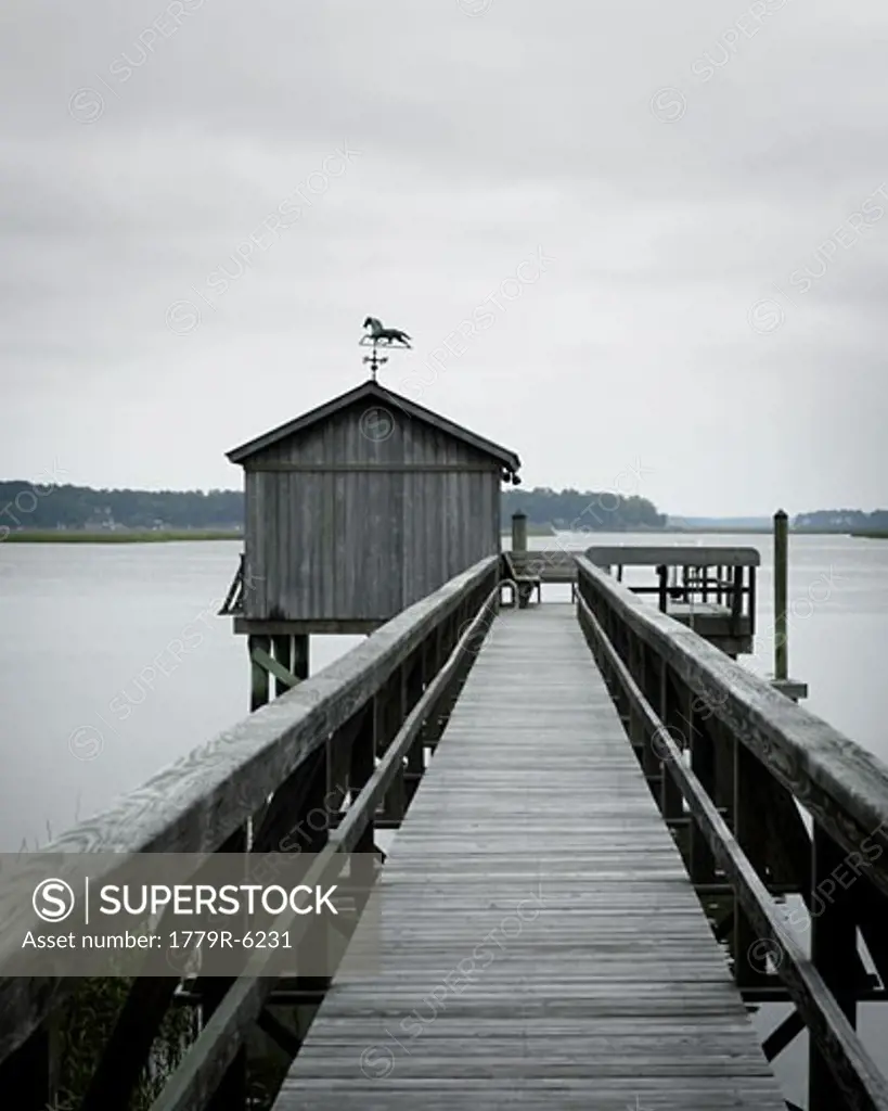 Pier and boathouse on lake under overcast sky