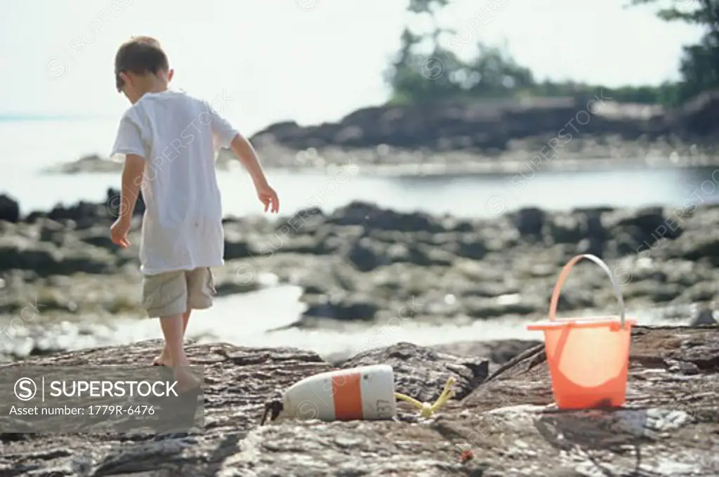 Young boy walking on rocks at coast