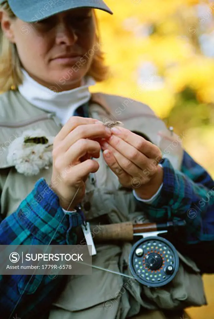 Woman attaching fly hook to fishing line