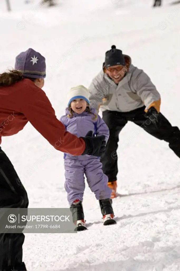 Young girl learning to ski with parents