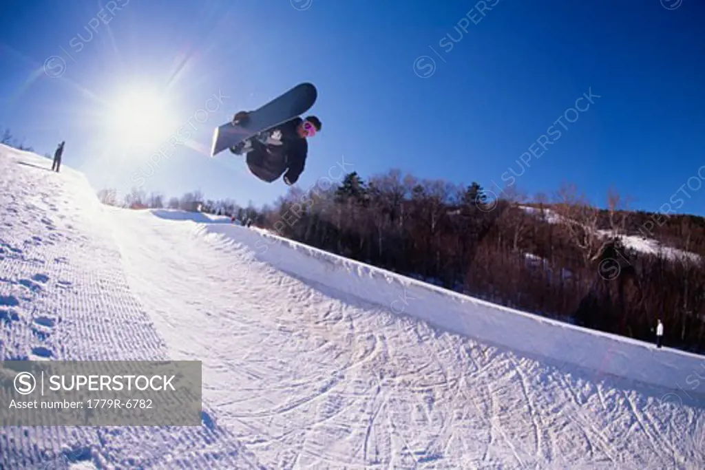 Snowboarder catching air in half pipe