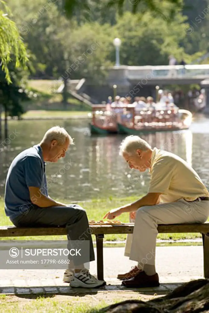 Senior men playing checkers on park bench