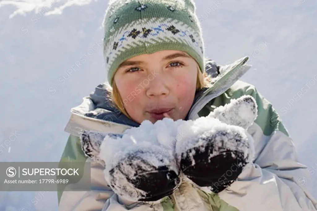 Teenage girl blowing snow from handful