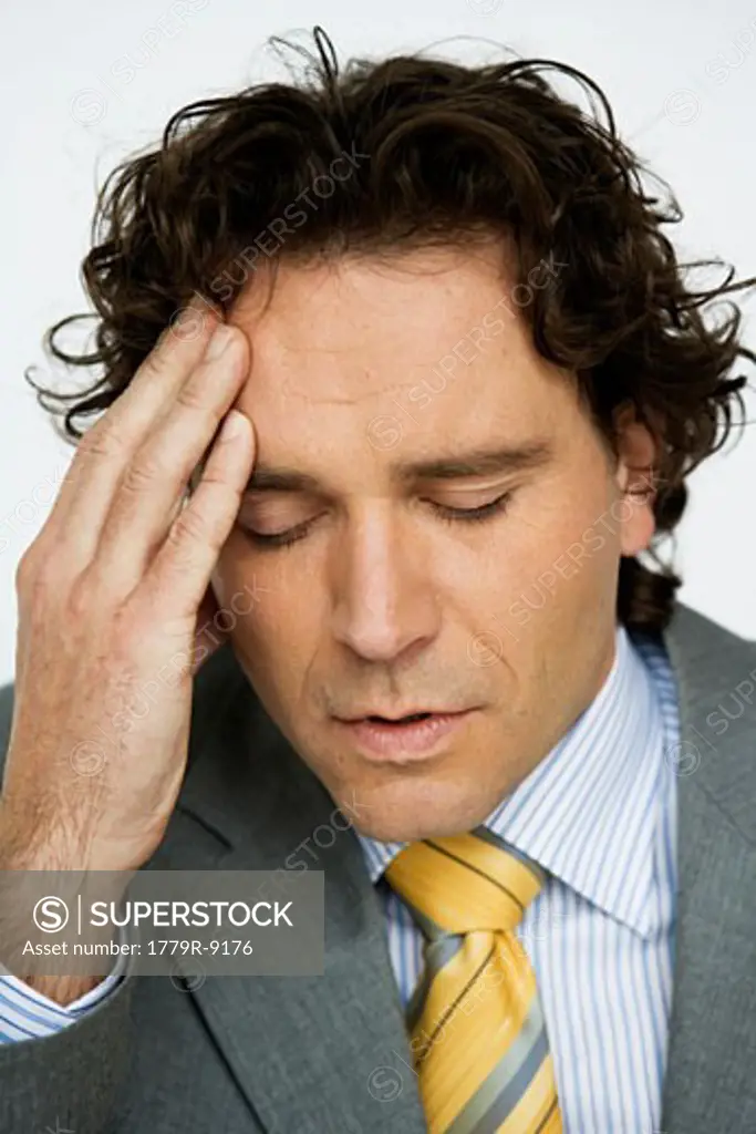 Young businessman rubbing his forehead