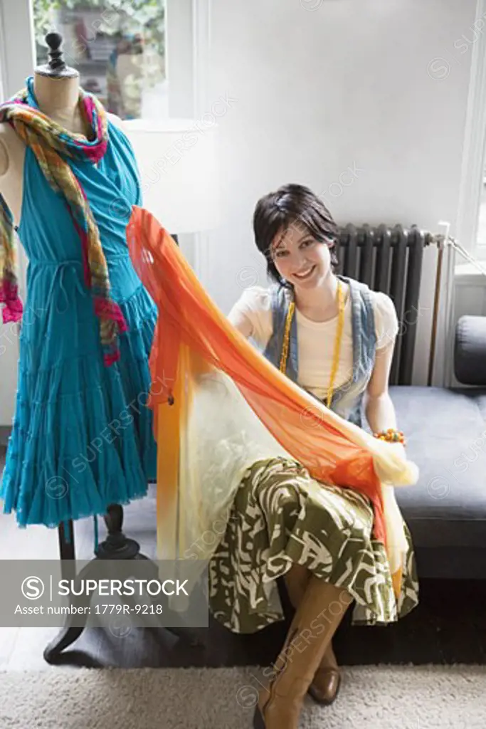 Female clothing designer with fabric and dressmaker's dummy