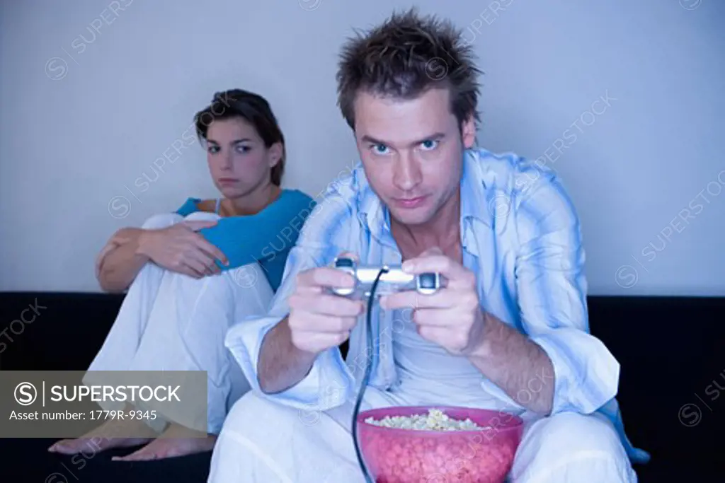 Annoyed woman watching boyfriend play video games