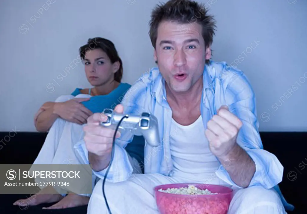 Annoyed woman watching boyfriend play video games