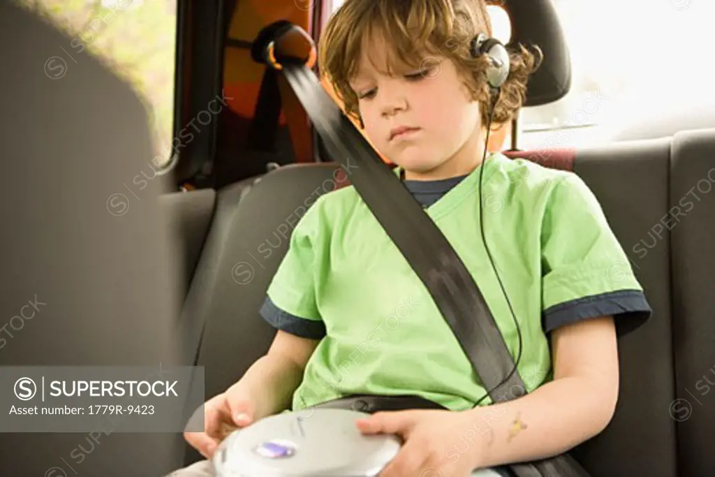 Young boy listening to headphones in backseat