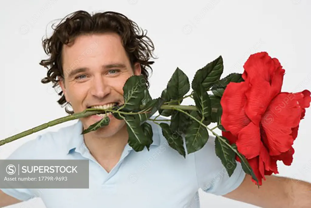 Man holding oversized flower between his teeth
