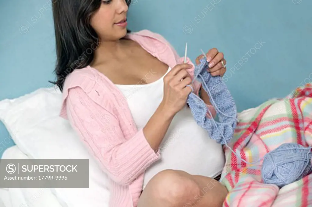 Pregnant Hispanic woman knitting