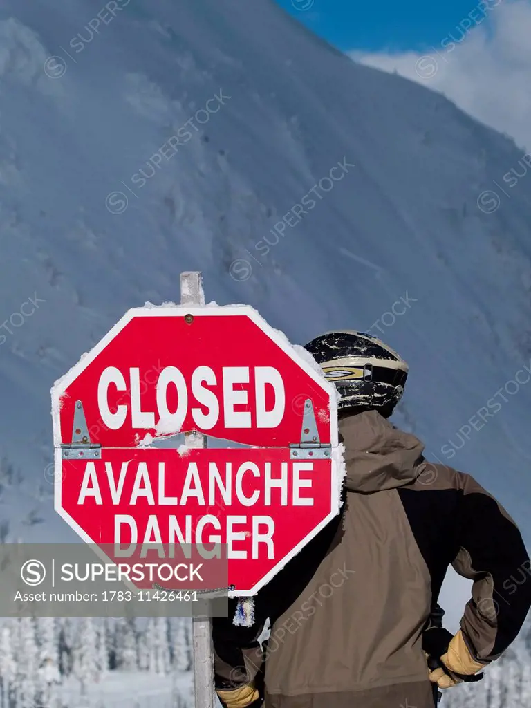 Helmeted Skier Stands Behind 'closed Avalanche Danger' Sign. Fernie, British Columbia, Canada.