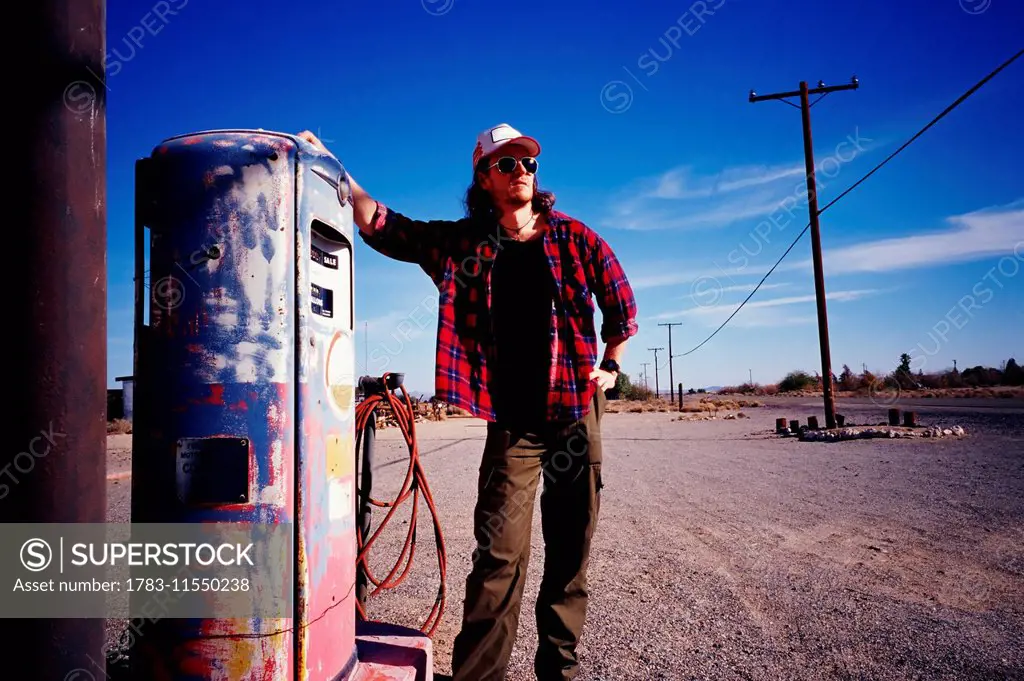 Man Standing Beside Pump At Old Gas Station